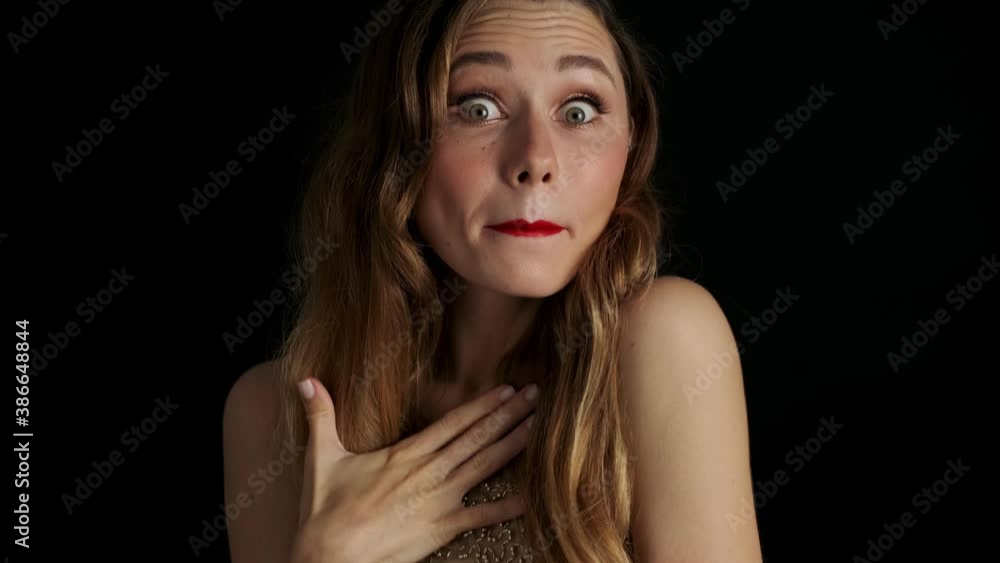 Young pretty shocked woman with red lipstick posing isolated over black background Young pretty shocked woman with red lipstick posing isolated over black background