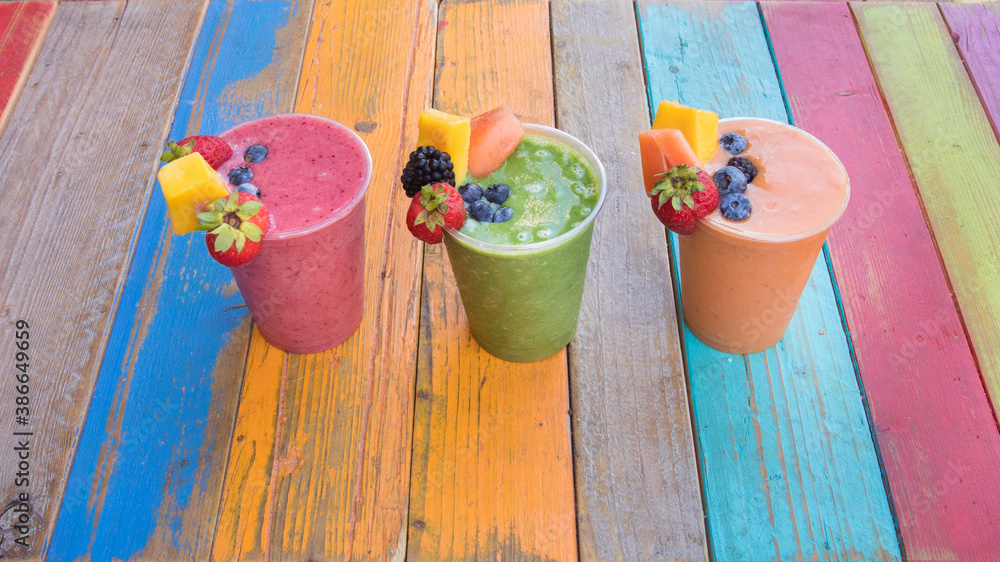 Colorful, tasty and healthy fruit smoothies on a colorful wood table Colorful, tasty and healthy fruit smoothies on a colorful wood table
