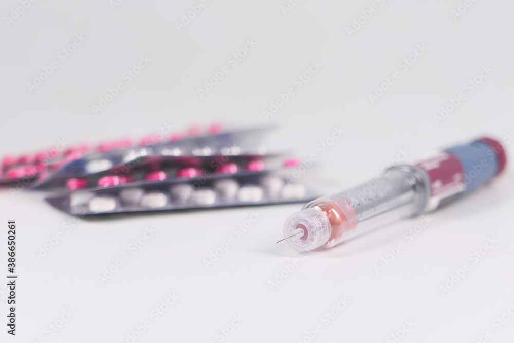 Obraz premium Insulin pen and pills on white background with copy space 
