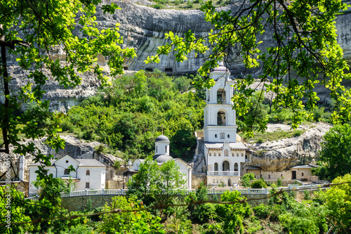 The buildings of the Assumption Cave Monastery in a scenic frame made of tree branches, Bakhchysarai, Crimea