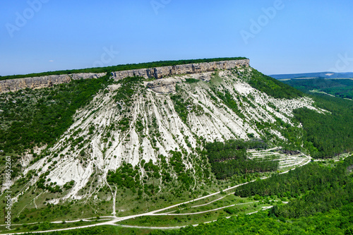 White rocks with wide plateau covered by forest. This classic view is part of Crimean mountains. Shot near city Bakhchisaray, Crimea photo