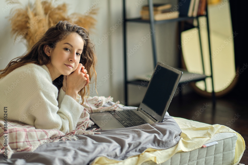 Fototapeta premium woman working online from home with laptop on her bed for new normal lifestyle during quarantine period from covid-19