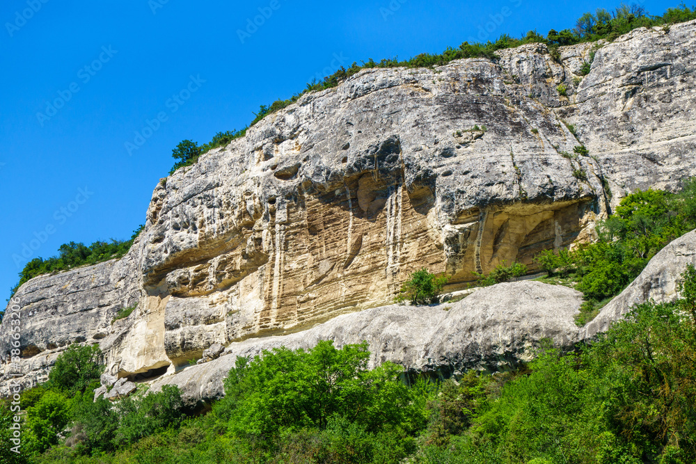 Massive rock formation overhanging the surrounding forest. Its top hides the ancient cave city Chufut Kale (Bakhchisaray, Crimea)