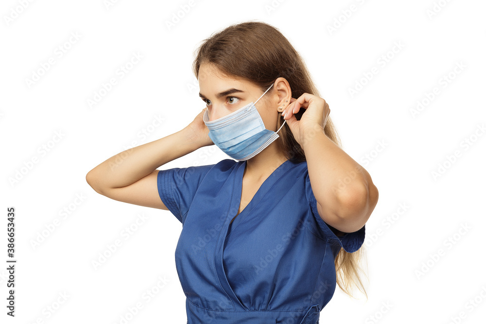 Beautiful young woman doctor surgeon putting on a protective disposable face mask isolated on white background. Virus protection concept. The modern viral threat of coronavirus Beautiful young woman doctor surgeon putting on a protective disposable face mask isolated on white background. Virus protection concept. The modern viral threat of coronavirus