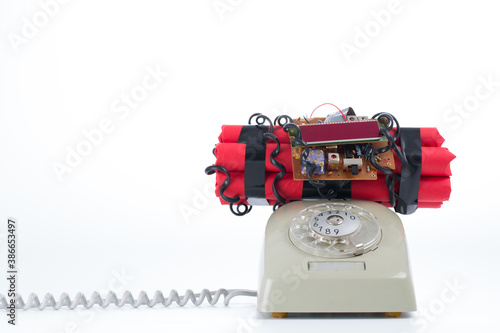 Studio photo of old vintage rotary telephone with time bomb on top, bright background.