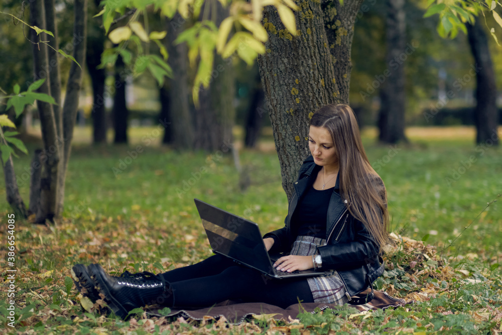 young woman works for a laptop in the park. the student is preparing for exams young woman works for a laptop in the park. the student is preparing for exams