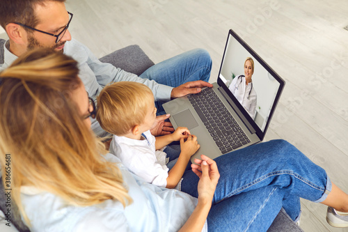 Mom, dad and their son listen to a doctor's consultation via video conference on a laptop. photo