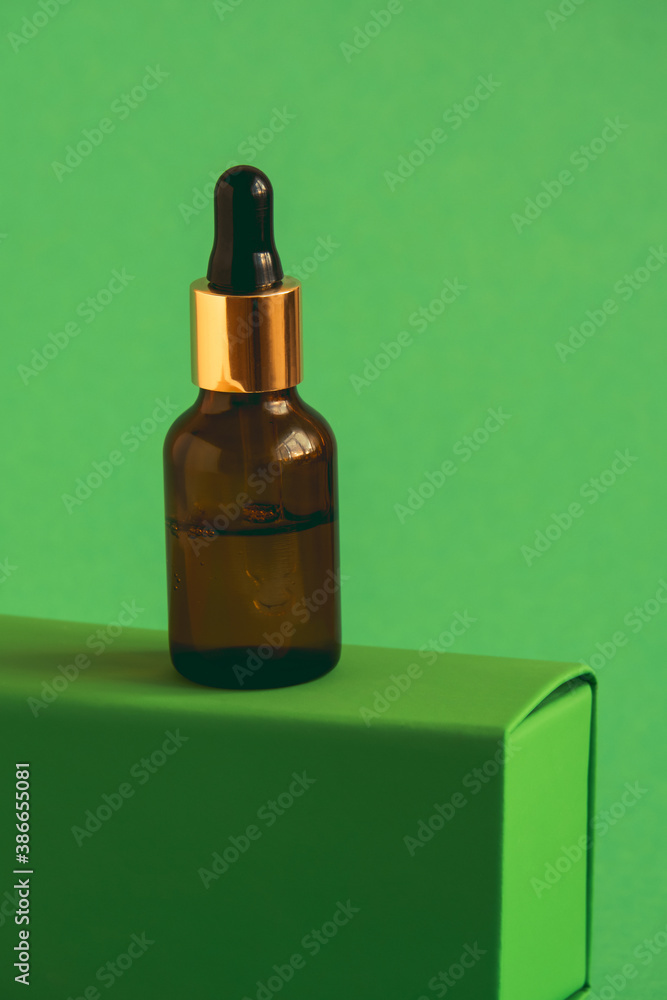 glass bottle with cosmetic product with pipette on a green pedestal on a green background - obrazy, fototapety, plakaty 