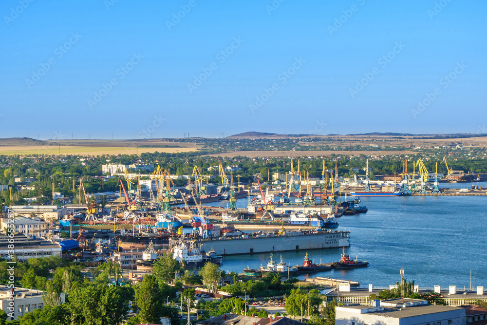 Panorama of sea port in Kerch, Crimea. There are lots of ships, cranes & docks. Villages & steppe are on far background