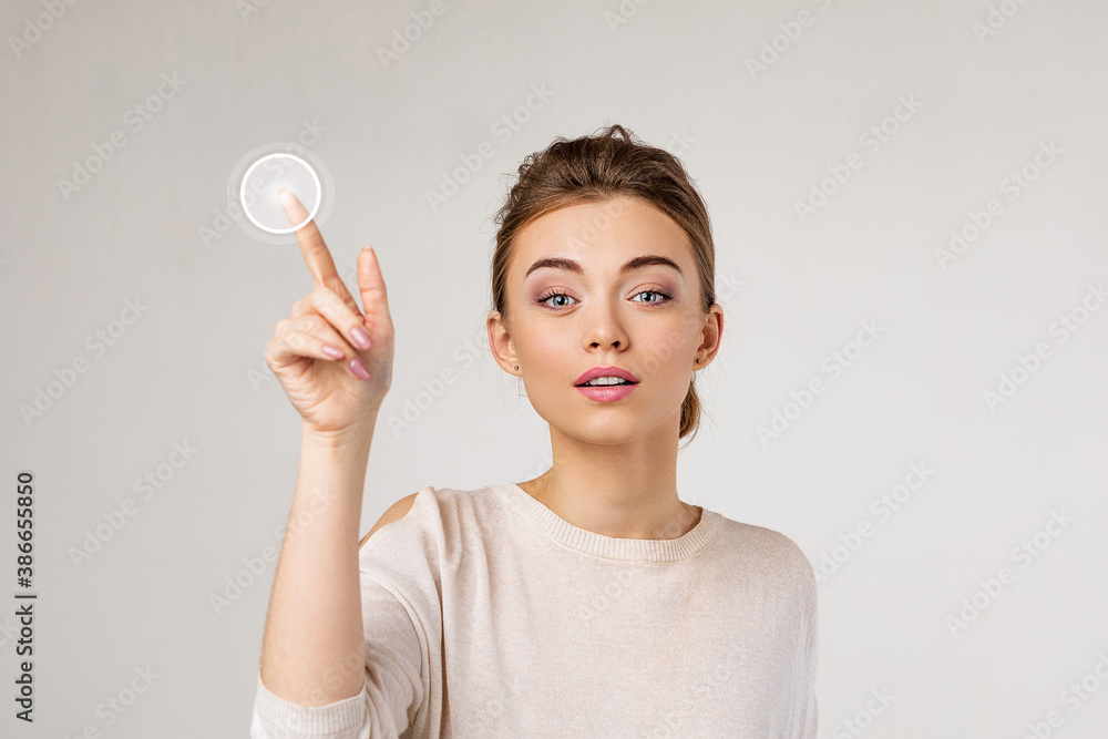 young beautiful woman pressing virtual button and looking at the camera on gray background. young beautiful woman pressing virtual button and looking at the camera on gray background.