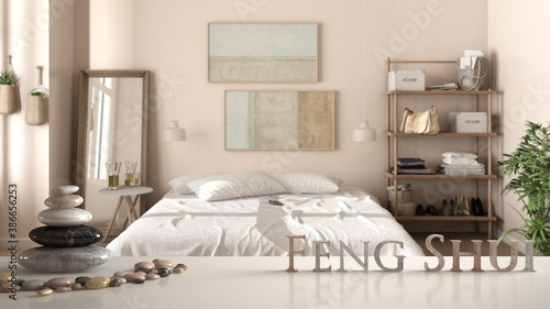 White table shelf with pebble balance and 3d letters making the word feng shui over country rustic wooden bedroom with soft white bed with duvet, zen concept interior design