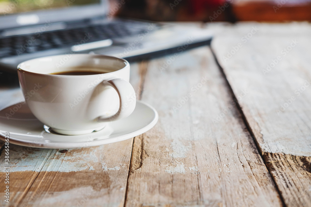 .A cup of coffee and a notebook computer on the desk .A cup of coffee and a notebook computer on the desk