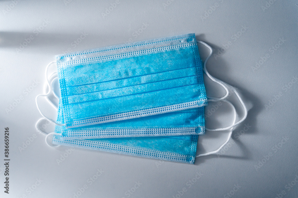 Fototapeta premium Medical mask on white table. Surgical mask with rubber ear straps. Virus protection concept. Healthcare and medical equipment in the hospital. Antiviral medical protection against corona virus.