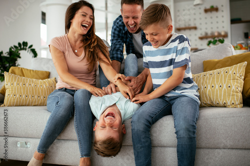 Young family enjoying at home. Mother and father tickling son.