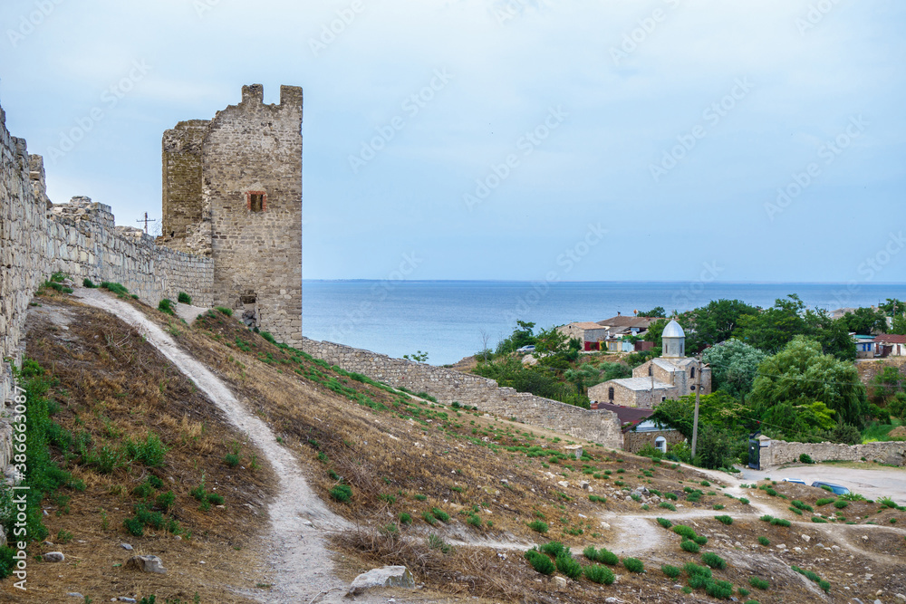 Inside of Genoese fortress in Feodosia, Crimea. Medieval walls & tower are on foreground. Church of St. John The Baptist & Black Sea are on background