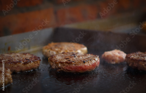 Burger meat frying on hot pan in close up.Ground beef for hamburger cookin on grill in hot oil.Minced meat patty grilling in closeup.Delicious natural steak grilled hot sandwich in fastfood restaurant photo