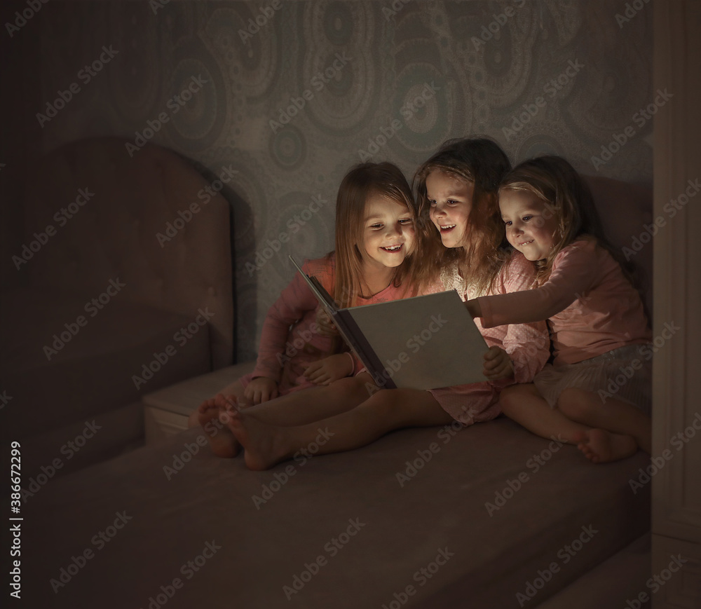 three girls sisters on the bed reading a book and laughing
three girls sisters on the bed reading a book and laughing