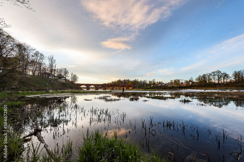 Late evening sunset view of old historic brick bridge over river Venta. Late evening sunset view of old historic brick bridge over river Venta.