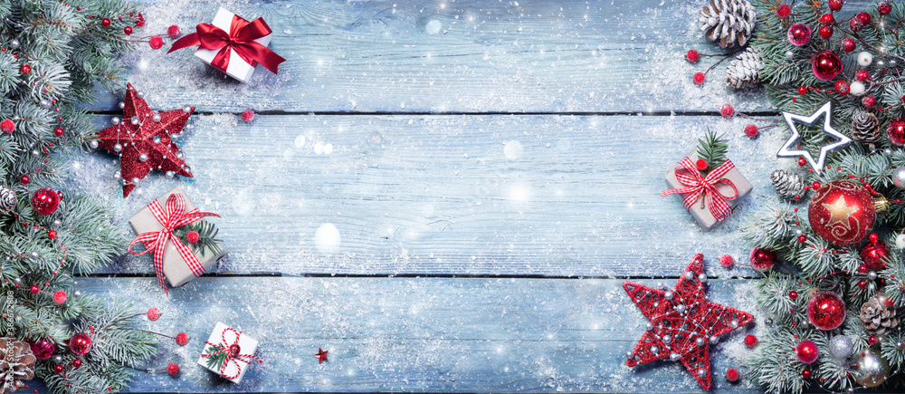 Fototapeta premium Fir Branches With Red Ornament And Rustic Giftbox On Snowy Plank - Christmas Background
