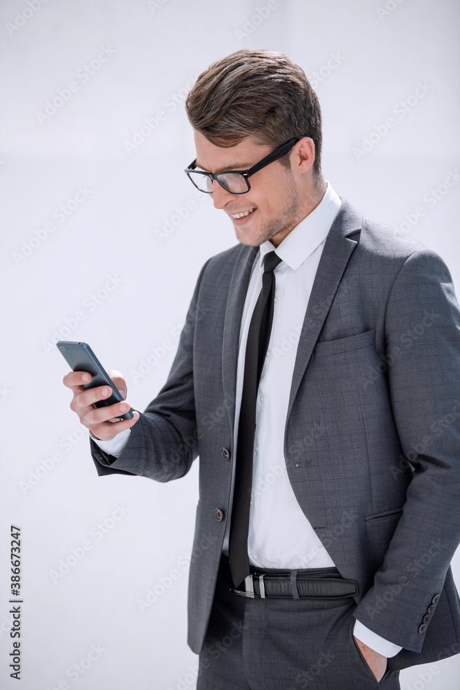 smiling businessman looking at the screen of his smartphone smiling businessman looking at the screen of his smartphone