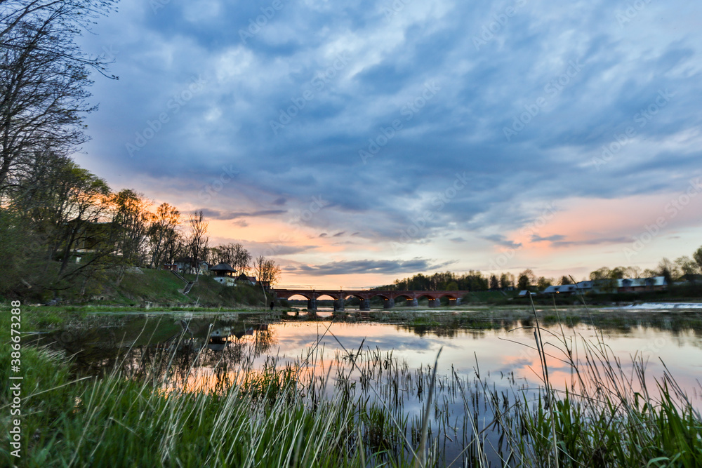 Landscape view of old brick bridge over river Venta in a late sunset evening.
