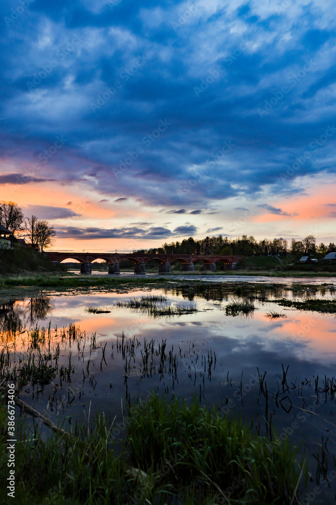Landscape view of old brick bridge over river Venta in a late sunset evening.