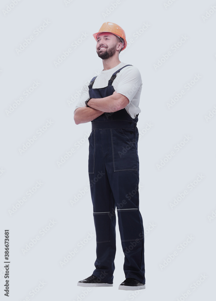 in full growth. smiling man in overalls and a safety helmet in full growth. smiling man in overalls and a safety helmet