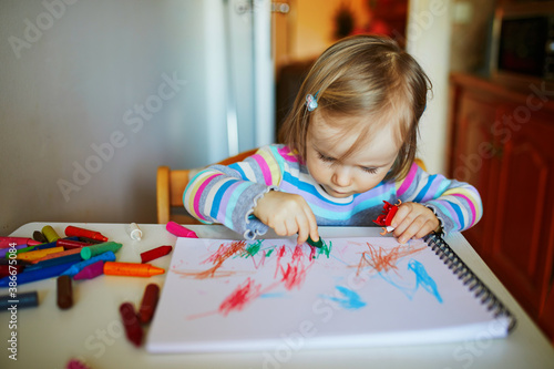 Adorable little girl painting with color pencils at home, in kindergaten or preschool photo