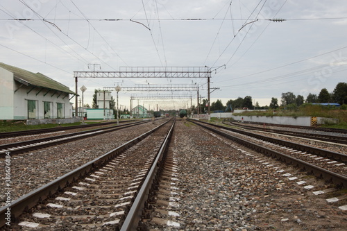 Russian 1520 mm empty railway tracks in perspective and station house, railroad landscape on a cloudy summer day