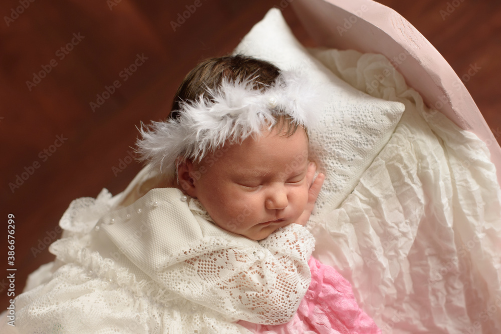 Newborn girl sleeping in small wooden bed with white layer and floral decor.
Newborn girl sleeping in small wooden bed with white layer and floral decor.