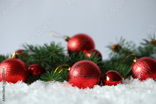 Beautiful Christmas balls and fir branches on snow against grey background. Space for text