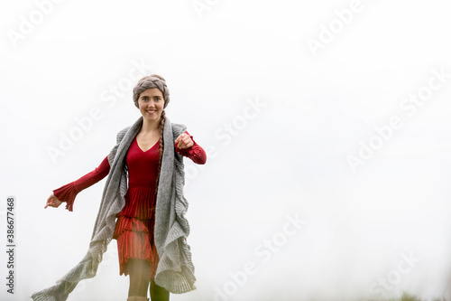 Frau in rotem Kleid bewegt sich ausgelassen und heiter vor hellem Himmel, zufrieden und selbstbewußt, Freude ausstrahlend. photo