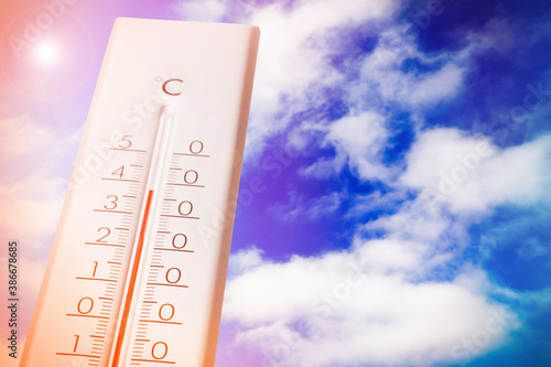 Weather thermometer showing high temperature and blue sky with clouds on background