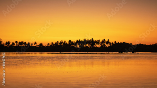 A bright orange sunset sky reflecting in the calm ocean near Ngwesaung, Myanmar