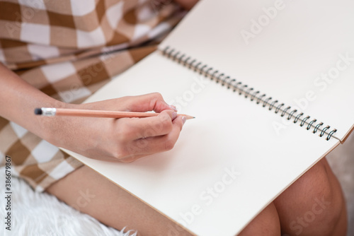 Woman sitting on sofa and hands writing something on a notebook