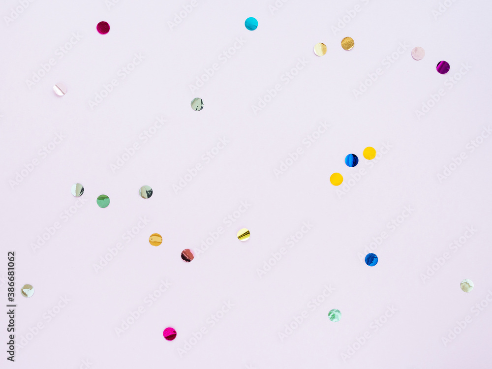 Multi-colored shiny round confetti on a pink background, top view, copy space, flat lay Multi-colored shiny round confetti on a pink background, top view, copy space, flat lay