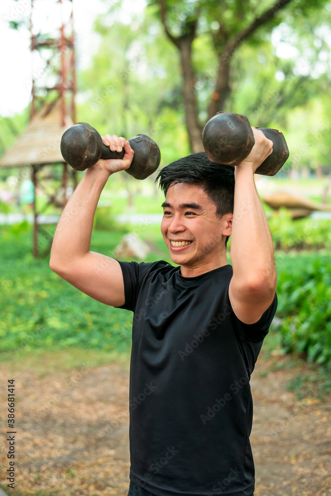 asian guy training his shoulders with dombbell in the park