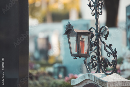 Sorrow concept. Red candle in iron lantern at the cemetery, funeral photo