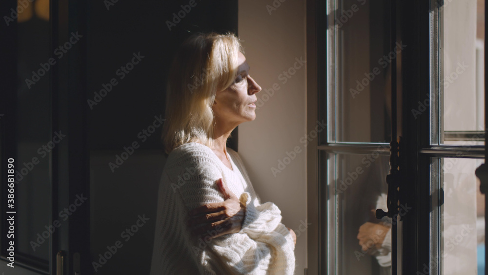 Side view of pensive mature businesswoman looking out of window indoors Side view of pensive mature businesswoman looking out of window indoors
