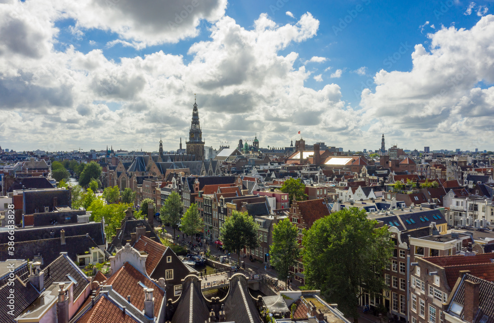 Beautiful Amsterdam Cityscape from Aerial rooftop perspective above Canals and Church Tower View with Blue Sky and big clouds
