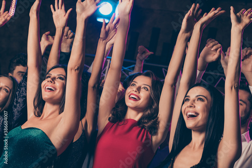 Low angle photo of girls resting dancing celebrating prom at party in night club dancing together hands over head smiling