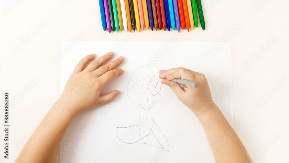 Сhild draws on paper wax crayons interesting drawing on white background Сhild draws on paper wax crayons interesting drawing on white background