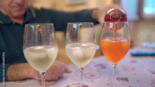 Wallpaper Mural Close-up of bartender's hand holding alcohol bottle and pouring aperol in wineglasses with prosecco and ice cubes, man preparing refreshing summer fizzy cocktail drink for party or celebration event Torontodigital.ca