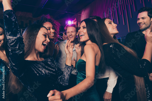 Photo of young people dancing in night club with neon lights chilling together laughing enjoying music celebrating new year xmas
