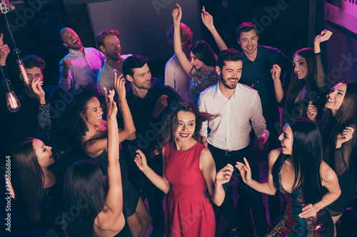 Attractive elegant cheerful glad crowd dancing having fun enjoying celebratory corporate event in dark night music club indoors