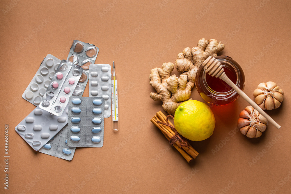 Natural cold and flu home remedies versus synthetic pills and drugs, top view. Honey glass pot