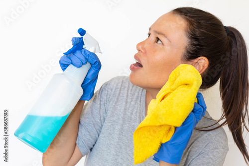 Quadro em tela A woman cleaning and sanitizing her home with a rag and spray bottle, afraid of bacteria and germs