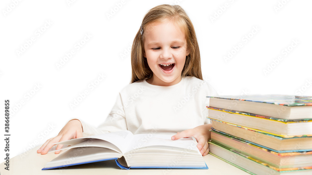 little cheerful girl sitting at the table and reads a books laughs on a white background. little cheerful girl sitting at the table and reads a books laughs on a white background.