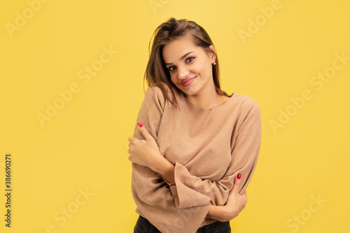 Cute posing. Portrait of young caucasian woman isolated on yellow studio background with copyspace. Beautiful female model. Concept of human emotions, facial expression, sales, advertising, youth.