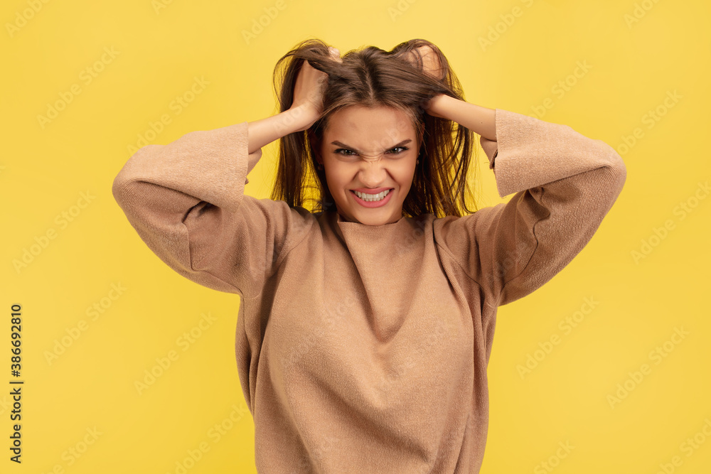 Angry, crazy. Portrait of young caucasian woman isolated on yellow studio background with copyspace. Beautiful female model. Concept of human emotions, facial expression, sales, advertising, youth. Angry, crazy. Portrait of young caucasian woman isolated on yellow studio background with copyspace. Beautiful female model. Concept of human emotions, facial expression, sales, advertising, youth.